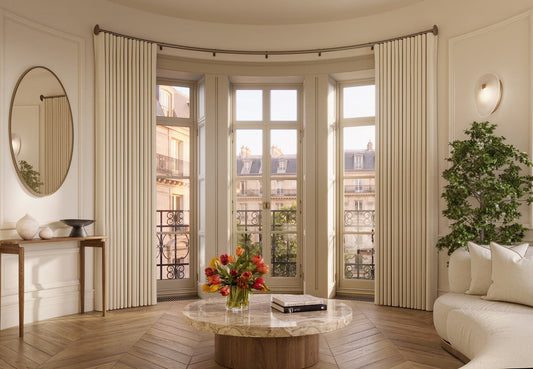Silent Gliss SG 7670 Motorised Metropole curtain pole in a luxury lounge with floor-to-ceiling linen curtains on a curved bay window