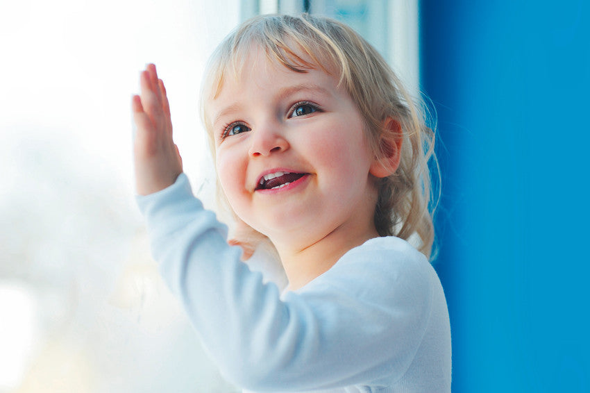 Smiling child with hand against a window